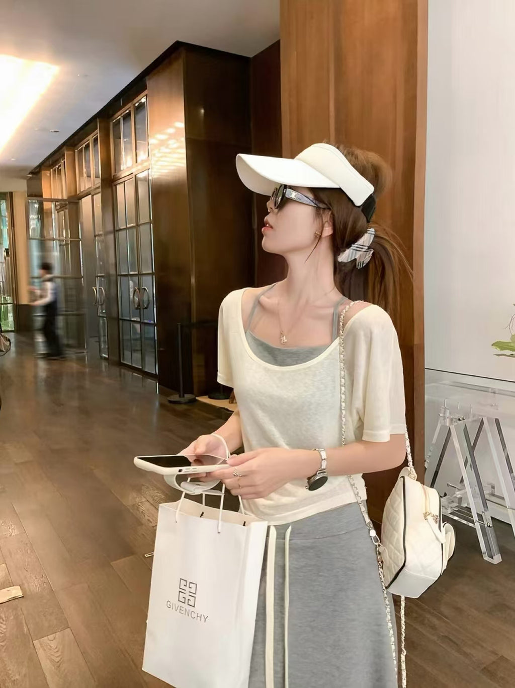 3-piece set - model wearing cream top and grey skirt, holding Givenchy shopping bag