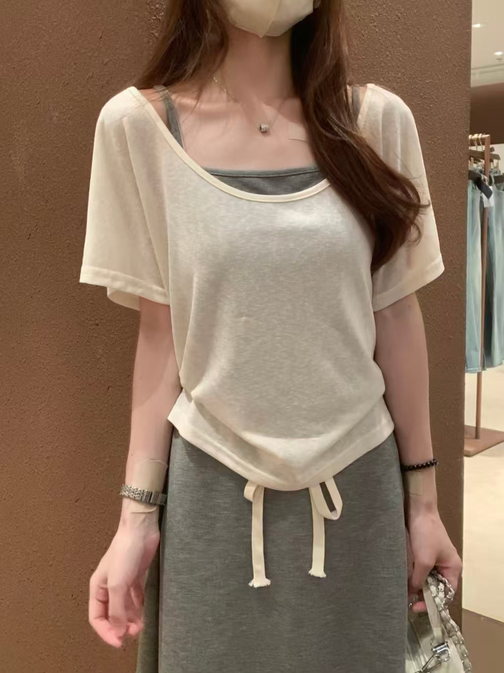 Close-up of cream knit top - drawstring hem detail and square neckline layering with grey camisole